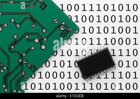 An electronic circuit board and integrated circuit chip with printed digital data binary ones and zeros in background. Stock Photo