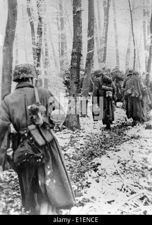 German army fights the American troops along the Western Front in December 1944. The Nazi propaganda text dated 30 December 1944 reads: 'The winter battle in the West. Despite bitter resistance by the opponents, our troops continue to advance in the West. Our picture shows: German infantry marching through a snow-covered beech forest.' Fotoarchiv für Zeitgeschichtee - NO WIRE SERVICE Stock Photo
