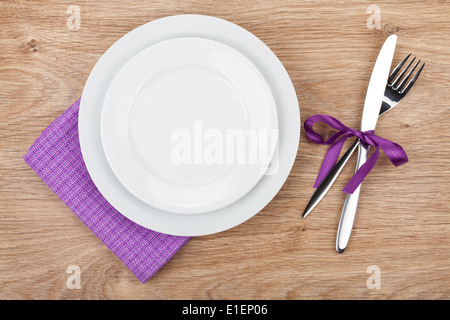 Fork with knife, blank plates and napkin. On wooden table background Stock Photo