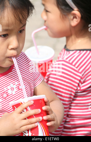 2 sisters having fun with coca cola, both wearing red shirts Stock Photo