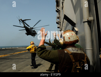 U.S. Marines from the 15th Marine Expeditionary Unit wave as a Marine Corps CH-53E Super Stallion helicopter takes off from the Stock Photo
