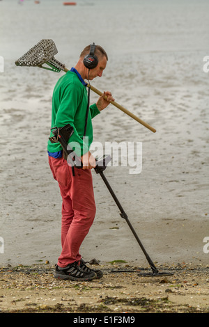 Man using metal detector on beach, Poole Harbour, UK Stock Photo