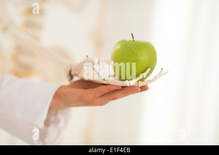 Closeup on medical doctor woman with human skeleton hand holding apple Stock Photo