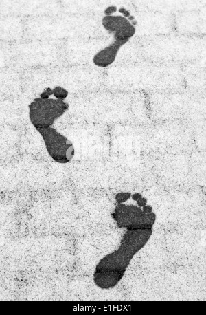 Three barefoot footprints on the frosty pavement Stock Photo