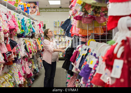 Denver, Colorado - A pregnant 26-year-old woman shops for baby clothes at a resale shop. Stock Photo