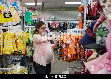 Denver, Colorado - A pregnant 26-year-old woman shops for baby clothes at a resale shop. Stock Photo