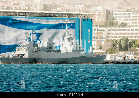 Eilat. A 'Saar 5' missile frigate anchored along a large Israeli flag painted on a hangar in a military port. Stock Photo