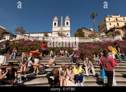 Tourists sitting on the Spanish Steps, with the azaleas in flower in spring; Rome city center, Italy Europe Stock Photo