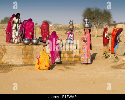 India, Rajasthan, Jaisalmer, Thar Desert, Khuri, women dressed in colourful saris collecting water from village well Stock Photo