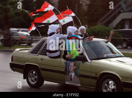 Damascus, Syria. 3rd June, 2014. Syrian supporters of presidential candidate Bashar al-Assad wave national flags with portraits of him during a march in Damascus, capital of Syria, on June 3, 2014. Syria's Higher Judicial Committee has extended the presidential voting period for another five hours until midnight Tuesday, according to the official SANA news agency. Credit:  Bassem Tellawi/Xinhua/Alamy Live News Stock Photo