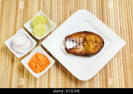 Delicious, crisply fried, crusted seer/mackerel fish fillet served with shredded carrots, raw onion rings and lemon. Stock Photo