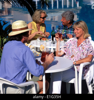 COUPLES EATING AND DRINKING BESIDE POOL Stock Photo