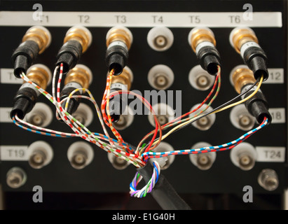 Chaotic arrangement of cables and connectors coming out of an electronic measuring device in an electronic engineering lab. Stock Photo