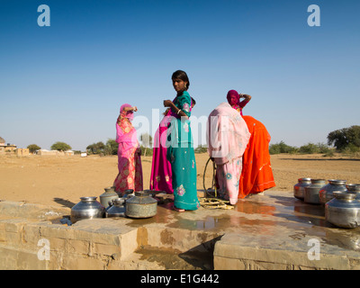 India, Rajasthan, Jaisalmer, Thar Desert, Khuri, colourfully dressed women collecting water from village well Stock Photo