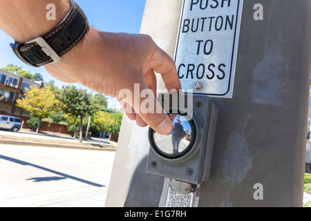 Push button to cross with sign, hand. Pedestrian crossing crosswalk. Man pushing a button to stop car traffic in intersection. Stock Photo