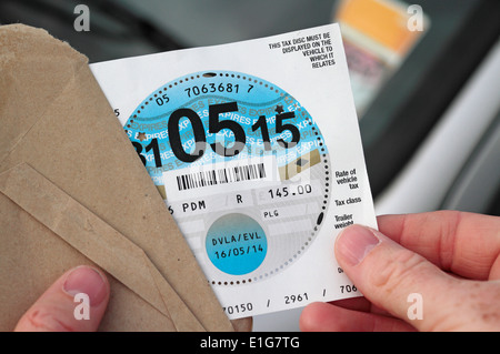 Opening an envelope containing a new UK road/car tax disc (UK car). Stock Photo