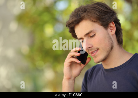 Handsome man talking on the mobile phone outdoor with green background Stock Photo