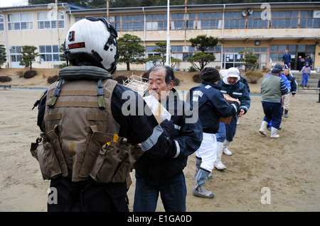 U.S. Naval Air Crewman 2nd Class Justin Dowd, left, hands a box of food to Japanese citizens during humanitarian relief efforts Stock Photo