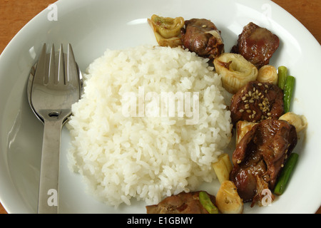 chicken's liver stir fried onions and sesame with steamed rice on wood table Stock Photo