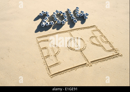 Simple line drawing of football pitch with soccer ball 2014 message in sand on Brazilian beach Stock Photo