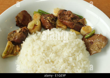 chicken's liver stir fried onions and sesame with steamed rice on wood table Stock Photo