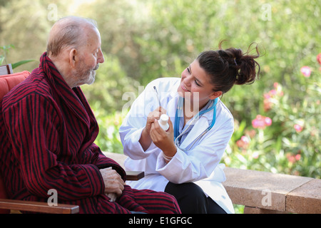 smiling Dr or nurse giving medication to senior patient. Stock Photo