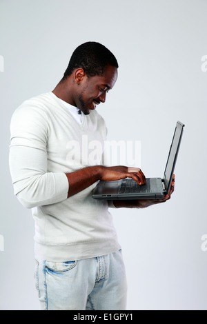 African man using laptop while standing up on gray background Stock Photo