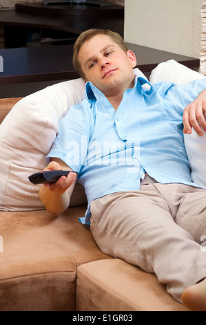 Man lying on sofa watching TV at home. Stock Photo
