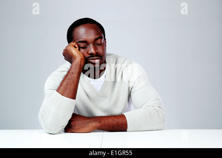 Portrait of african man sleaping at his workplace on gray background Stock Photo