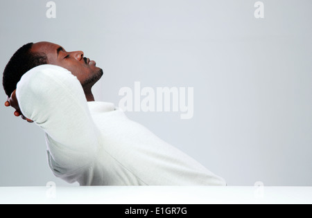 Relaxed african man sleaping at his workplace on gray background Stock Photo