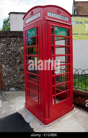 Old red telephone box being used to house a defibrillator machine in Southwold - these save lives Stock Photo