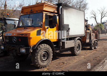 Three-quarter front view of a  Unimog 1250  four-wheel drive vehicle pulling a trailer-mounted chipping machine for tree surgery. Stock Photo