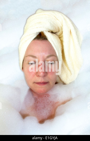 Mature woman surrounded by bubbles in during a luxurious bubble bath Stock Photo