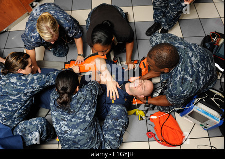 U.S. Navy hospital corpsmen roll Lt. Todd Leroux onto a stretcher during an emergency medical drill aboard the Nimitz-class air Stock Photo