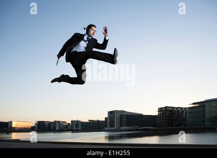 Mid adult businessman jumping mid air, Copenhagen harbor, Denmark Stock Photo