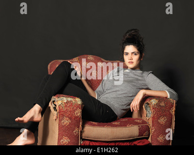Young woman sitting in armchair Stock Photo