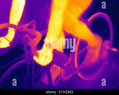Cropped thermal image of young male athlete in training, showing the heat of the muscles and of the bicycle tires Stock Photo