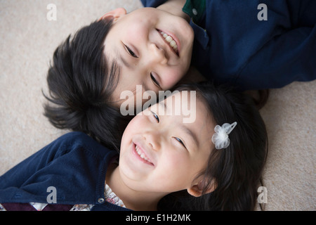 Portrait of brother and sister lying on carpet Stock Photo