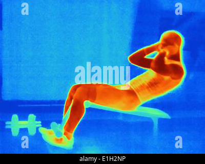 Thermal image of young man doing pull ups on weight bench. The image shows the heat produced by the muscles Stock Photo