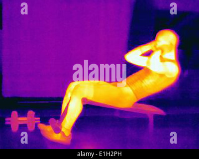 Thermal image of young male athlete doing pull ups on weight bench. The image shows the heat produced by the muscles Stock Photo