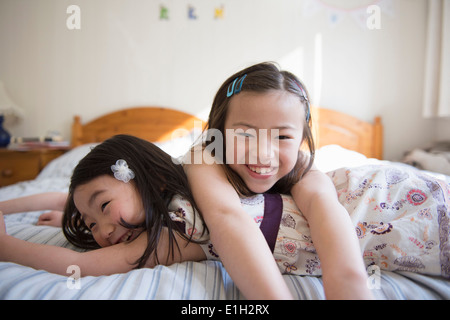 Two young female friends lying on bed