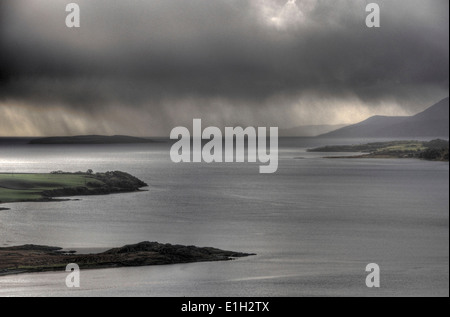 Rainclouds move across the sea at the Kyles of Bute in Scotland with land peninsulas and mountains and a sea loch Stock Photo