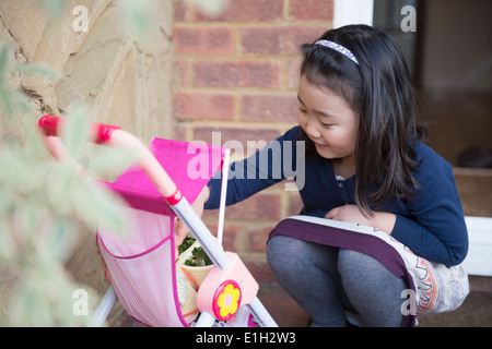 Young girl playing with toy pushchair