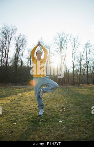 Young woman practicing yoga in field Stock Photo