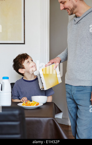 Father pouring cereal into son's bowl Stock Photo