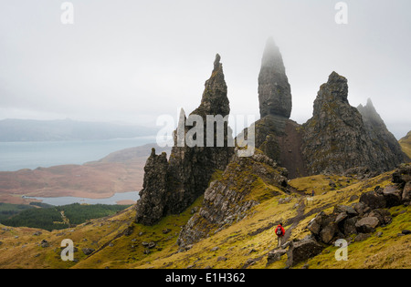 A tour guide walking towards The Old Man of Storr on a foggy spring day, Isle of Skye, Scotland Stock Photo