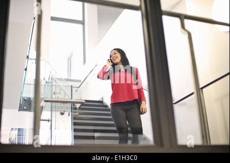 Young woman on staircase using cell phone Stock Photo