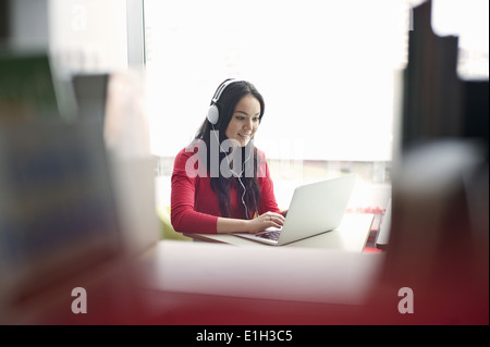 Young woman wearing headphones using laptop Stock Photo