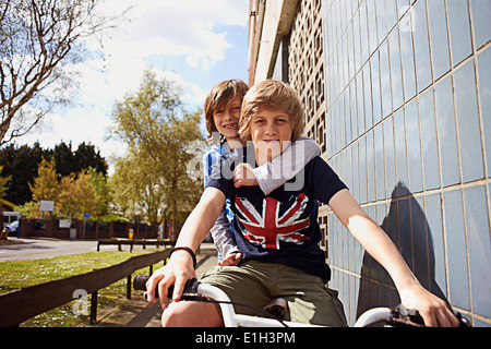Boys giving friend a ride on bike Stock Photo
