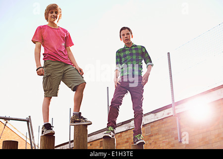 Boys standing on wooden poles Stock Photo